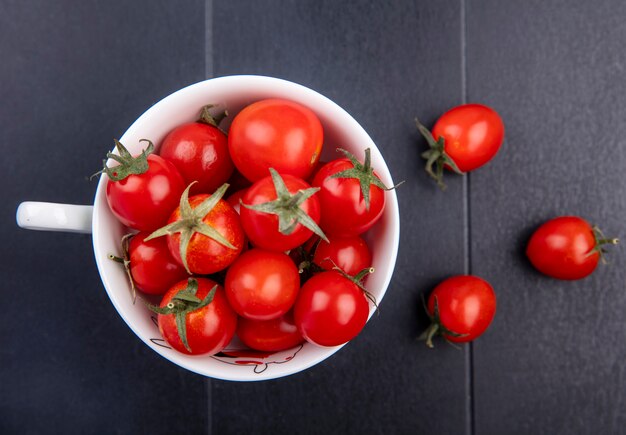 Top view of tomatoes in cup and on black surface