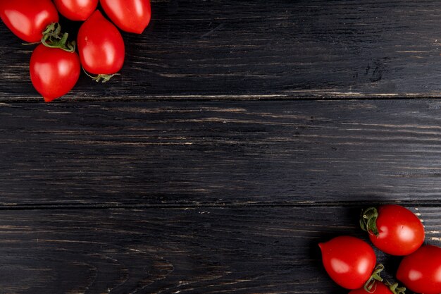 Top view of tomatoes on left and right sides and wooden surface with copy space