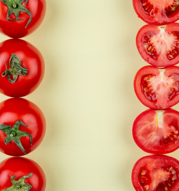 Top view of tomatoes on left and right sides on yellow surface with copy space