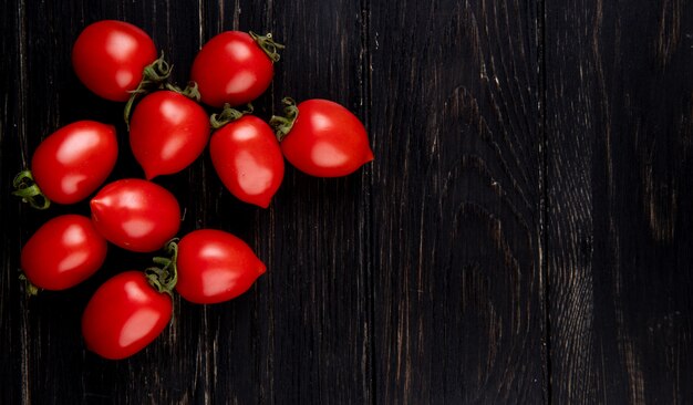 Top view of tomatoes on left side and wooden surface with copy space