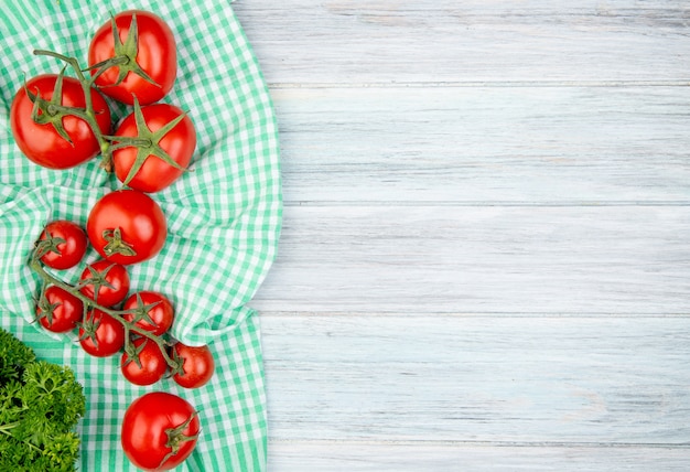 Top view of tomatoes on plaid cloth with coriander on wood with copy space