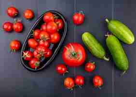 Foto gratuita vista dall'alto di pomodori nel piatto con cetrioli sulla superficie nera