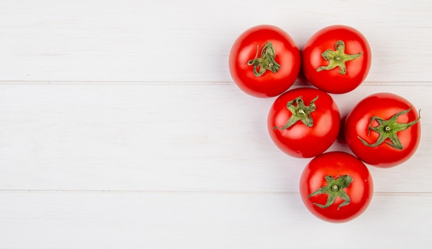 Top view of tomatoes on right side and wooden surface with copy space