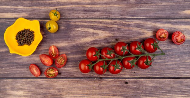 Top view of tomatoes with black pepper seeds on wooden surface