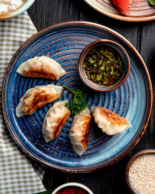 top view of traditional asian dumplings with meat and vegetables served with soy sauce on a plate on rustic table