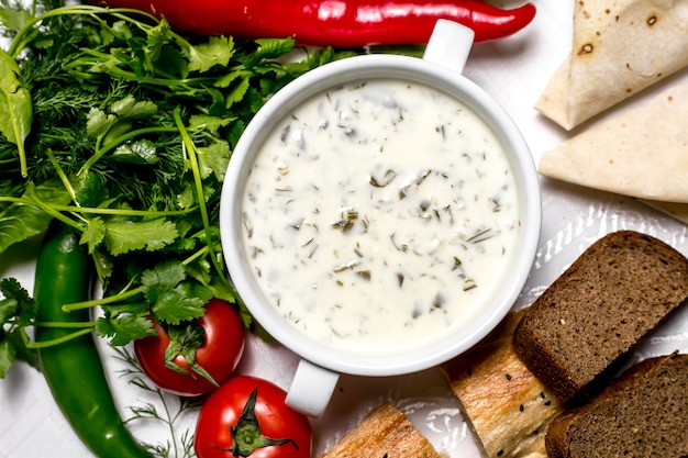 Top view a traditional azerbaijani dish dovga yogurt soup with herbs tomatoes and bread