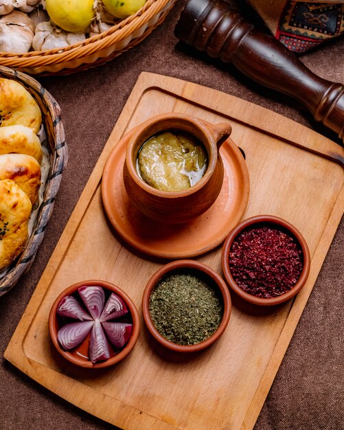 Top view a traditional azerbaijani dish piti in a pot with sumac dried herbs and onions on a tray