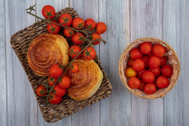 Top view of traditional azerbaijani pastry gogal on a wicker tray with tomatoes on a bucket on a grey wooden background