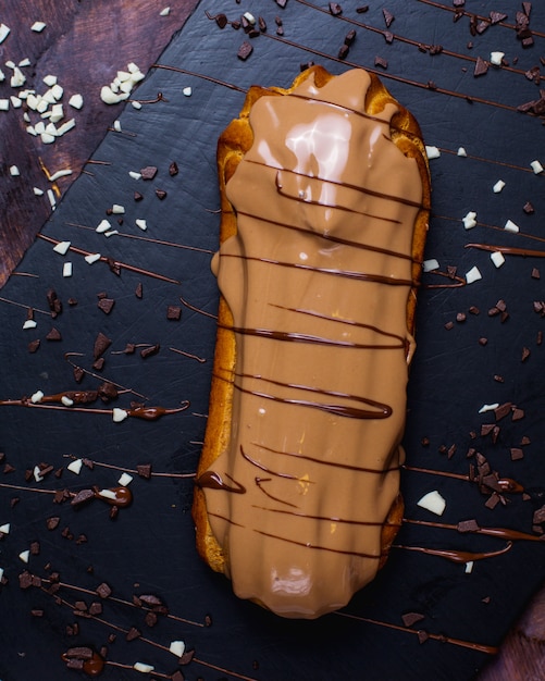 Foto gratuita vista dall'alto del tradizionale eclair francese decorato con cioccolato al latte su una superficie di legno