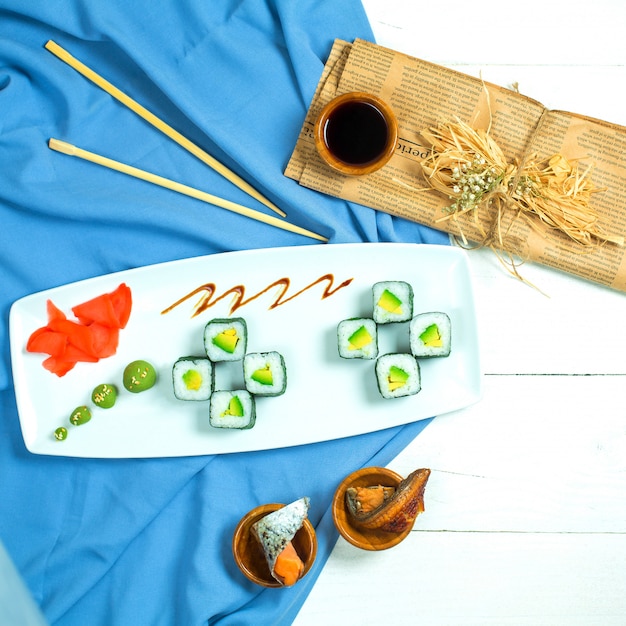 青と白の醤油生姜とわさびを添えてライスアボカドとクリームチーズの伝統的な日本料理の黒巻き寿司のトップビュー