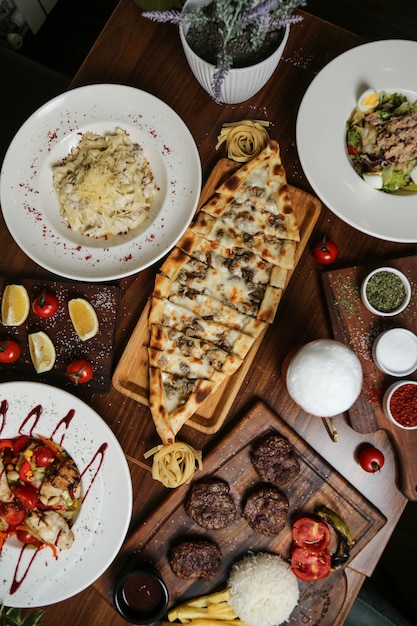 Foto gratuita vista dall'alto di un piatto tradizionale turco carne pide con formaggio su un supporto e altri piatti e spezie sul tavolo