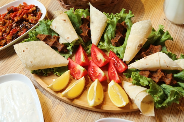 Top view a traditional turkish dish raw cutlet kyufta with pita bread tomatoes and lemon with lettuce on a stand