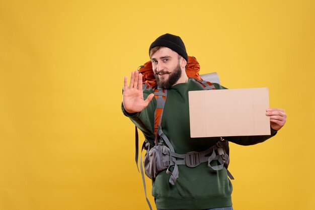 Top view of travel concept with confident young guy with packpack and holding free space for writing showing five