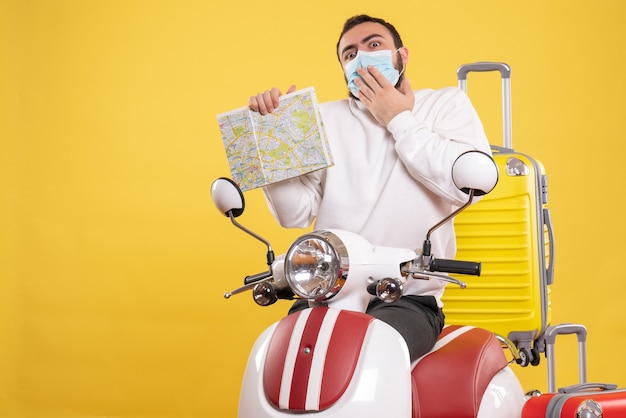 그것에 노란색 가방과 함께 오토바이 근처에 서서지도를 들고 의료 마스크에 혼란스러운 남자와 여행 개념의 상위 뷰