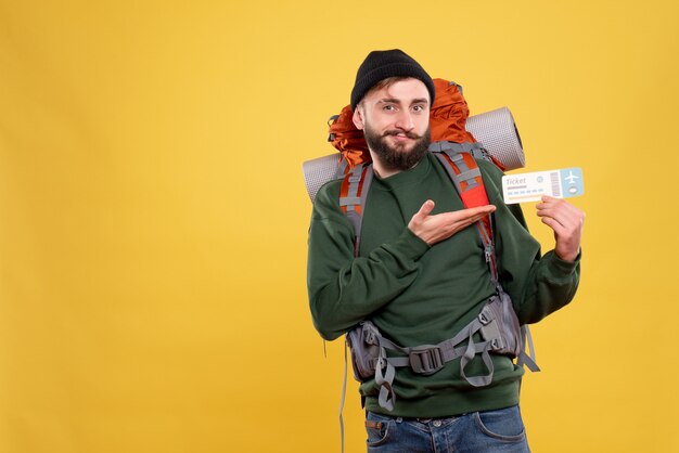 Top view of travel concept with smiling happy young guy with packpack and holding ticket