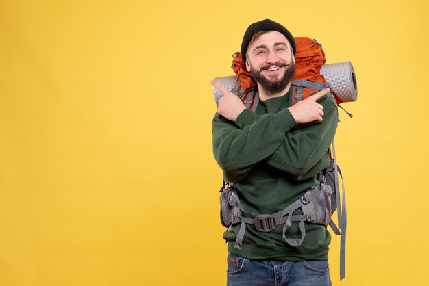 Top view of travel concept with smiling happy young guy with packpack pointing up in both sides