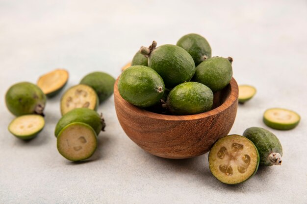 Top view of tropical fresh feijoas on a wooden bowl with feijoas isolated on a grey surface