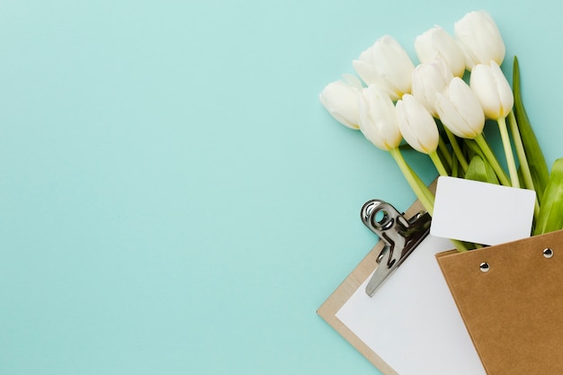 Top view tulip white flowers and notepad with copy space