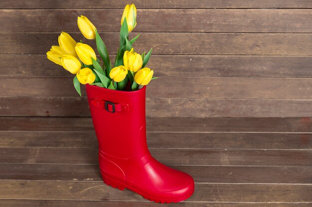 Top view of tulips and water boot on wooden surface