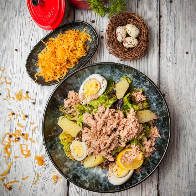 Top view tuna salad in plate with eggs, potato and eggs on wooden table