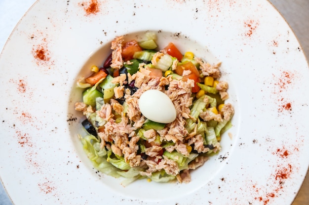 Вид сверху салат из тунца с вареным яйцом на тарелке