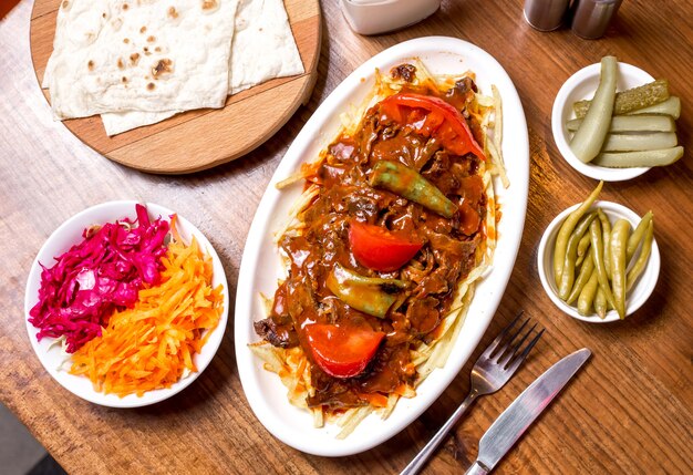 Top view of turkish beef kebab garnished with spicy tomato sauce served with prickles