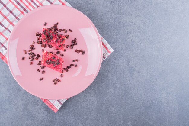 Top view of Turkish delight rahat lokum and dry raisins on pink plate.