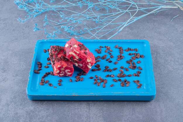 Top view of Turkish delight rahat lokum with pistachios and dry raisins on blue wooden board