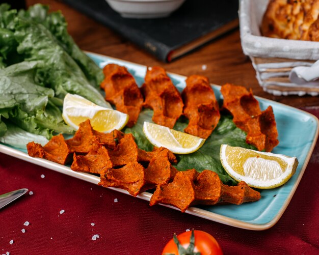 Top view of turkish food cig kofte with lemon and lettuce on a wooden table