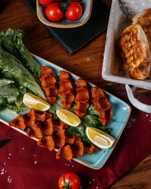 Top view of turkish food cig kofte with lemon and lettuce on a wooden table