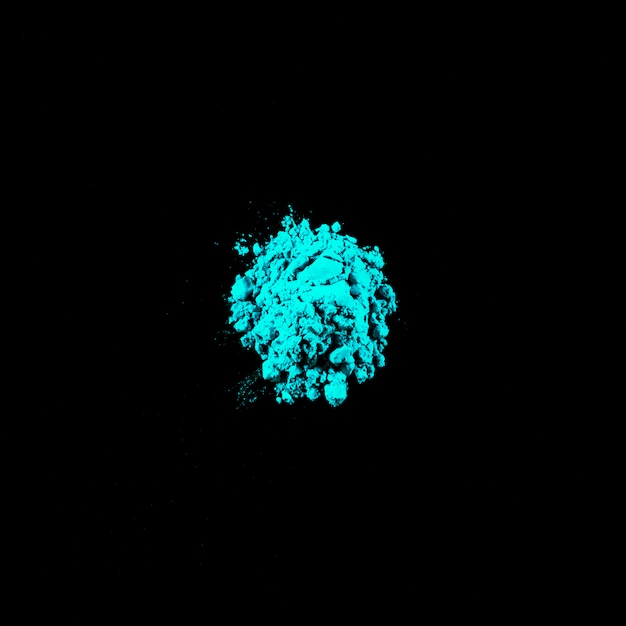 Top view of turquoise holi powder on middle of black background