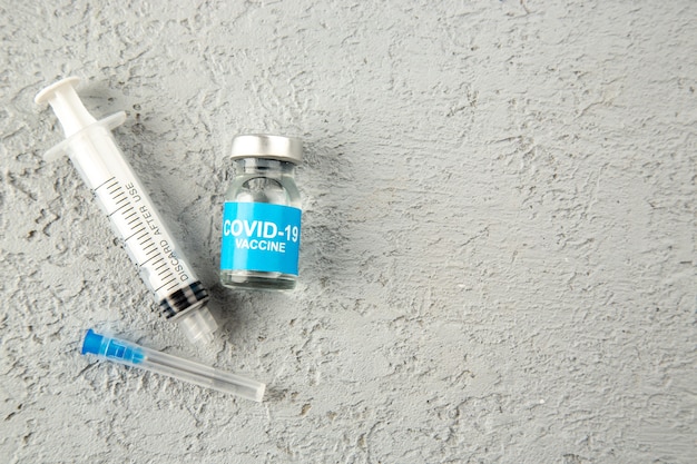 Top view of two empty syringe and covid- vaccine on the right side on gray sand texture background with free space