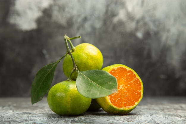 Top view of two fresh whole green tangerines with leaves and one cut in half tangerine on gray background footage