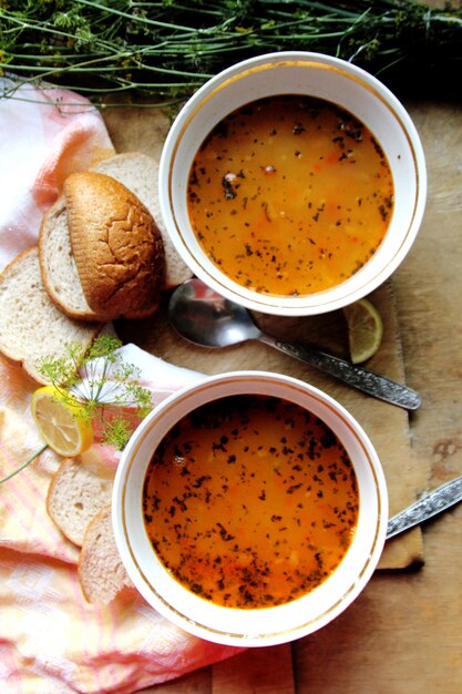 Top view two lentil soups with lemon dill and slices of bread