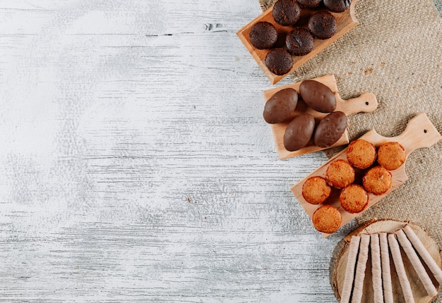 Top view types of cookies in cutting board and sack cloth on white wooden