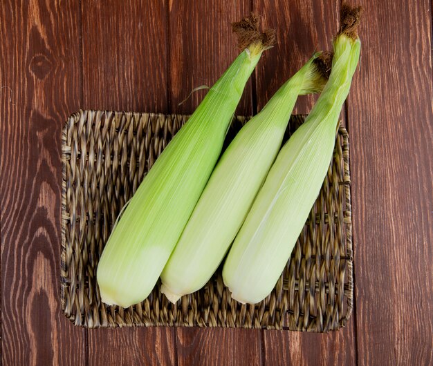 Top view of uncooked corns in basket plate on wood