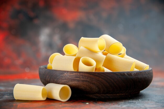 Top view of uncooked pastas inside and outside of the pot on black background