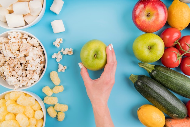 Top view unhealthy vs healthy food with hand holding apple