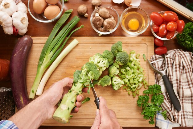 녹색 야채를 준비하는 인식 할 수없는 요리사의 상위 뷰