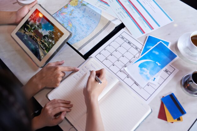 Top view of unrecognizable people planning vacation trip