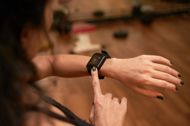 Top view of unrecognizable woman checking health app on her wrist gadget