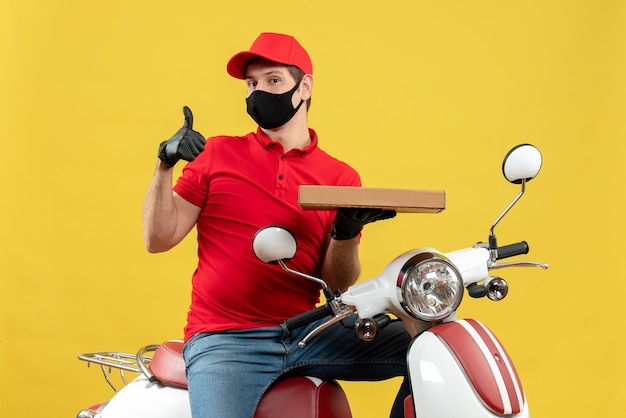 医療用マスクに赤いブラウスと帽子の手袋を身に着けている不満の宅配便の男性の上面図