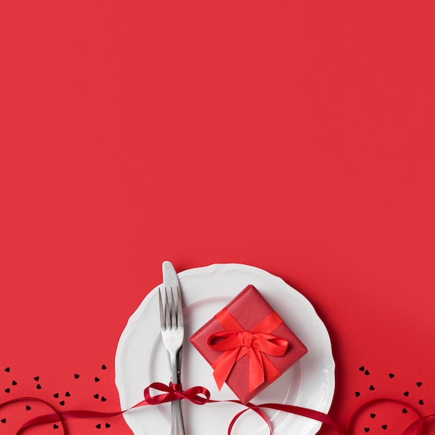 Top view of valentine's day gift on plate with ribbon and cutlery