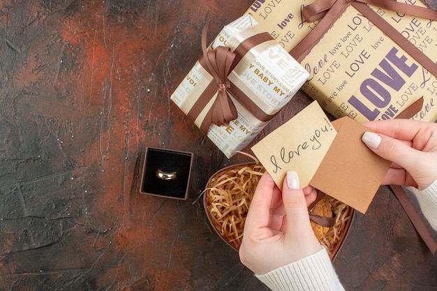 Вид сверху подарки на день святого валентина с кольцом и печеньем на темно-коричневом фоне, цвет подарка, чувство брака, праздничная пара