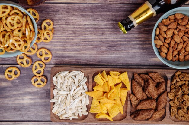 Top view of varied of beer snacks with a bottle of beer on rustic with copy space