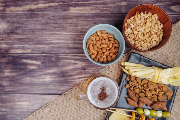 Top view of varied beer snacks with a mug of beer on sackcloth on rustic with copy space