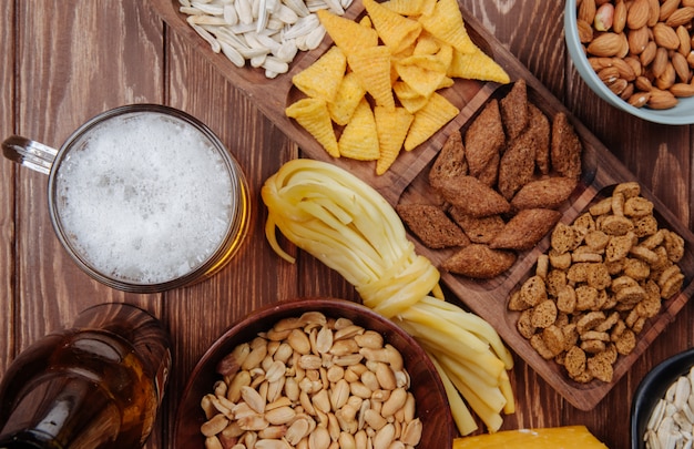 Top view of varied salty beer snacks with a mug of beer on rustic wood