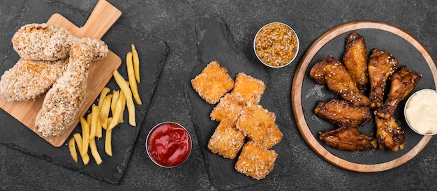 Top view of variety of fried chicken with sauces and french fries