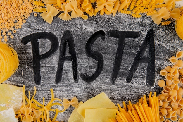 Foto gratuita vista dall'alto di varietà di tipi e forme di pasta italiana e pasta parola da farina su sfondo scuro