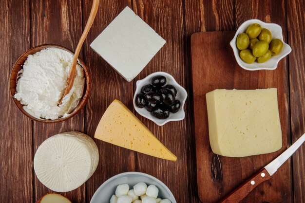 Top view of various kind of cheese and cottage cheese in a bowl with pickled olives on rustic table